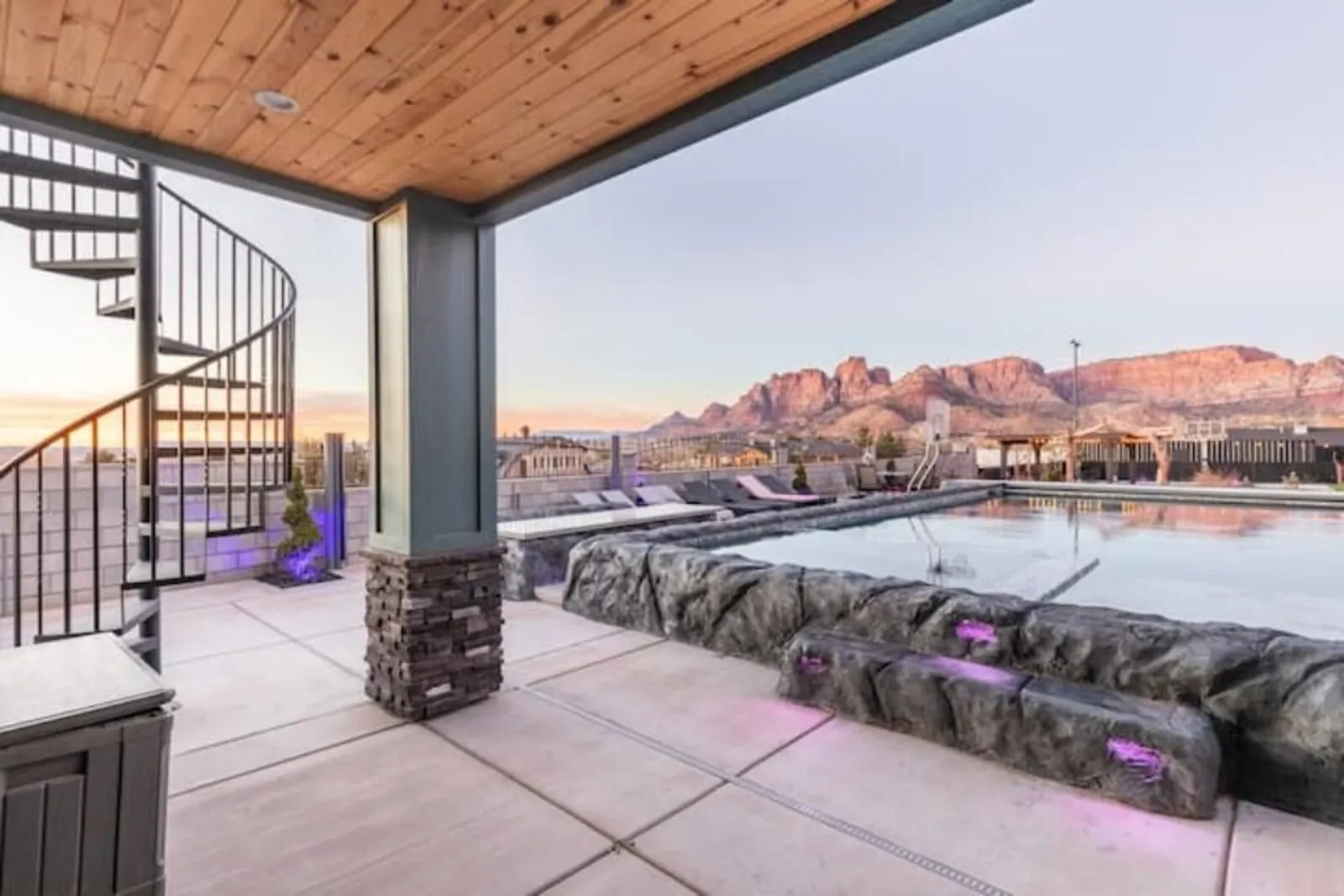 Covered patio with a spiral staircase overlooking the pool and red cliffs
