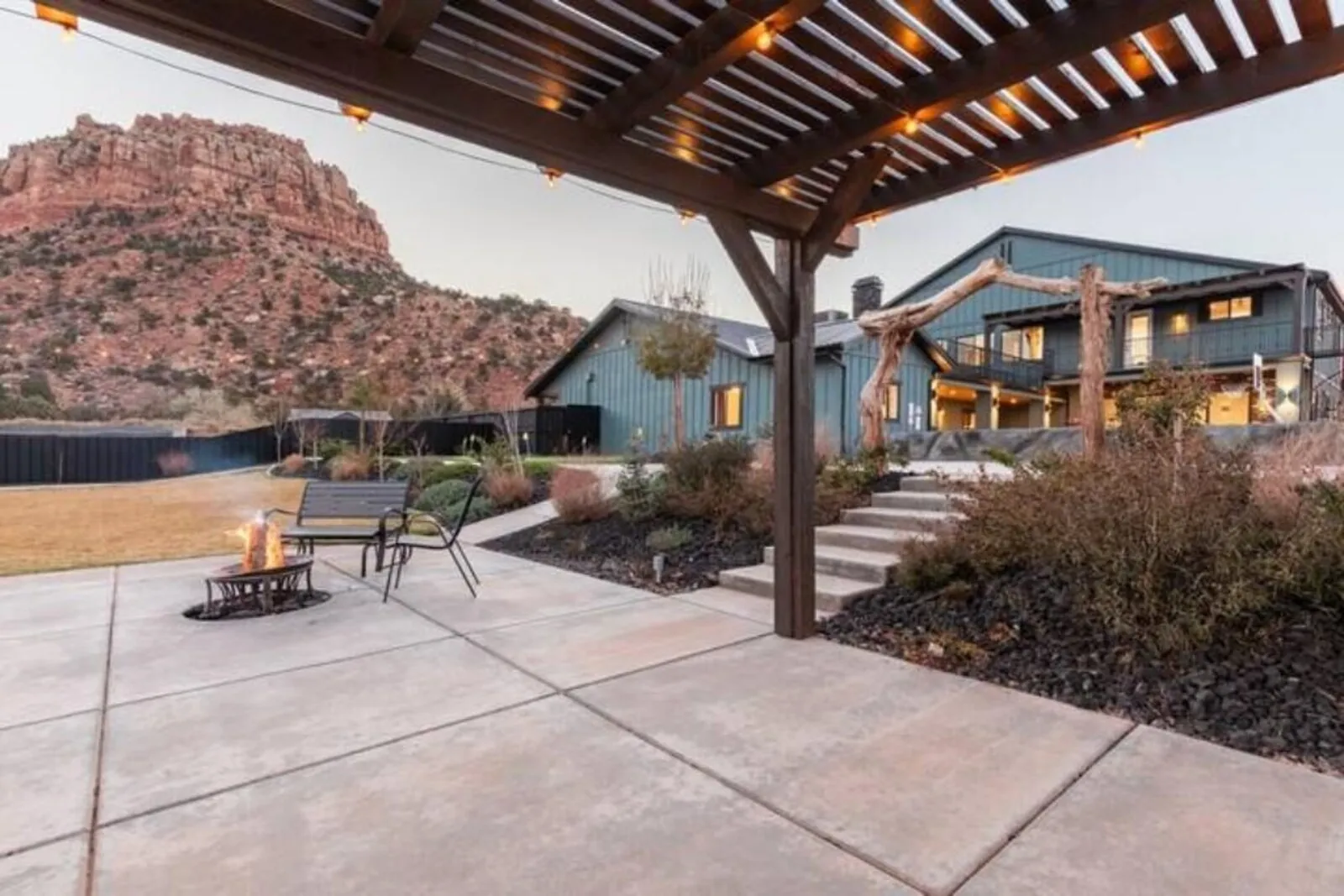 Patio firepit and pergola with the home and canyon walls in the background